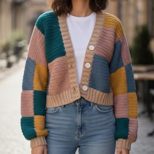 May include: A patchwork cardigan in shades of teal, mustard yellow, pink, and blue. The button-down sweater has a ribbed hem and cuffs, with a neutral-colored trim. The cardigan is worn over a white t-shirt and paired with blue jeans.
