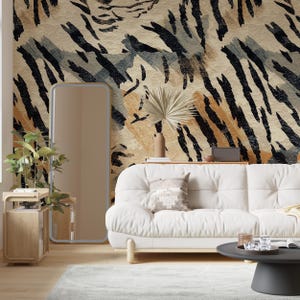 May include: A white tufted sofa with a patterned throw pillow, a tall rectangular floor mirror with a light frame, a wooden side table with a potted plant, and a round black coffee table against a wall with a tiger-stripe patterned wallpaper.
