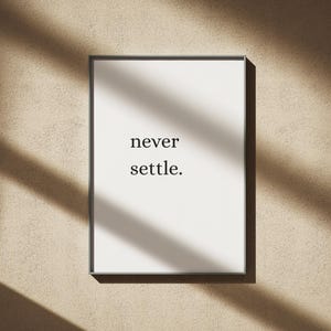 Può includere: Una stampa artistica da parete rettangolare in una sottile cornice nera con sfondo bianco e il testo nero never settle. centrato al centro. Il design utilizza un semplice carattere serif per visualizzare le due parole impilate l'una sull'altra.