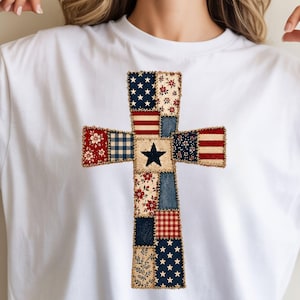 Könnte beinhalten: Weißes T-Shirt mit einem Patchwork-Kreuz-Design. Das Kreuz besteht aus verschiedenen Stoffmustern, darunter Sterne, Streifen, Blumendrucke und Vichy, in Rot, Weiß und Blau. In der Mitte befindet sich ein schwarzer Stern.
