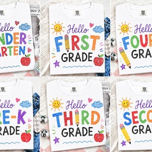Pode incluir: Uma coleção de seis camisetas brancas com gráficos coloridos em estilo de giz de cera. Cada camiseta exibe o texto Hello seguido de um nível escolar, incluindo Kindergarten, First, Second, Third, Fourth e Pre-K, acompanhados de ilustrações de sol, lápis, maçã e estrelas.