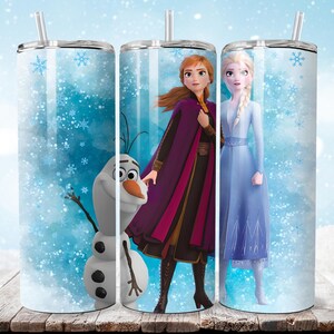 Puede incluir: Tres vasos de acero inoxidable con pajitas, con personajes de la pel&iacute;cula animada "Frozen". Los dise&ntilde;os incluyen a Anna, Elsa y Olaf sobre un fondo azul nevado con acentos de copos de nieve. Los vasos est&aacute;n sobre una superficie de madera.