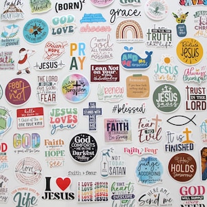 May include: A collection of colorful stickers with religious themes and inspirational quotes. The stickers feature phrases like "Jesus," "God," and "Faith," along with various designs, including rainbows, crosses, and hearts.