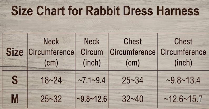 Puede incluir: Una tabla de tallas para un arn&eacute;s de vestido para conejo con texto marr&oacute;n oscuro sobre un fondo de veta de madera clara. La tabla enumera las tallas S y M con medidas de cuello y pecho en cent&iacute;metros y pulgadas, de 18 a 40 cm.
