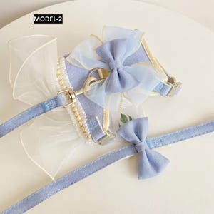 Puede incluir: Un arn&eacute;s para mascota de color azul claro con correa a juego etiquetado como MODEL-2. El arn&eacute;s presenta un gran lazo de organza transparente, una hilera de perlas blancas de imitaci&oacute;n y una anilla en D de metal. La correa incluye un lazo peque&ntilde;o.