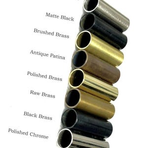 May include: A collection of metal tubes in various finishes, including Brushed Chrome, Matte Black, Brushed Brass, Antique Patina, Polished Brass, Raw Brass, Black Brass, and Polished Chrome. The text labels each finish. The tubes are cylindrical and have an open end.