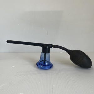 May include: A blue glass base attached to a black plastic nozzle and a black rubber bulb. The device features a long, slender horizontal tube extending from the central black cap, connected to a flexible black bulb on the right side.