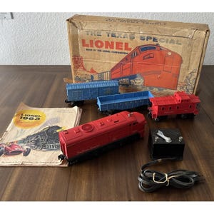 Può includere: Un set di trenini vintage Lionel The Texas Special che include una locomotiva rossa, un vagone merci blu, una gondola blu, un vagone di coda rosso, un trasformatore nero con cavo, un catalogo del 1963 e la scatola di cartone originale.