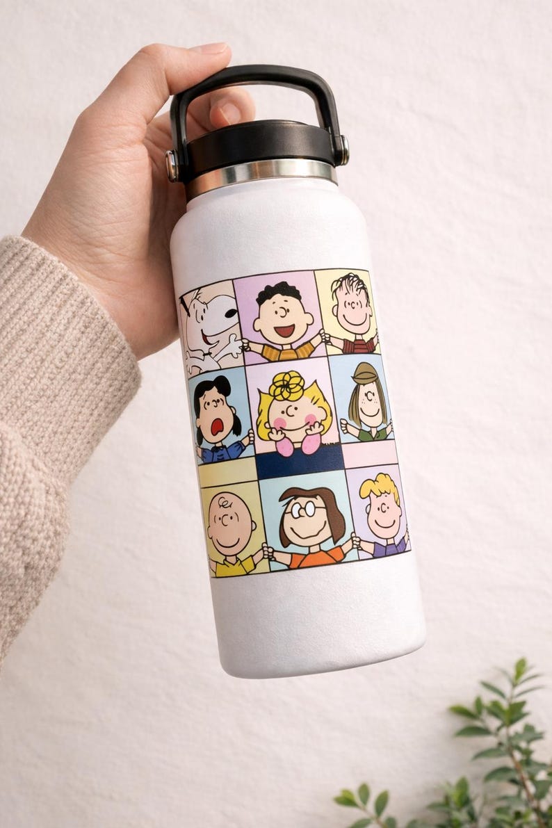 May include: White insulated water bottle featuring a colorful cartoon panel design with various characters. The bottle has a black handle and lid. A fun and functional item for carrying beverages.
