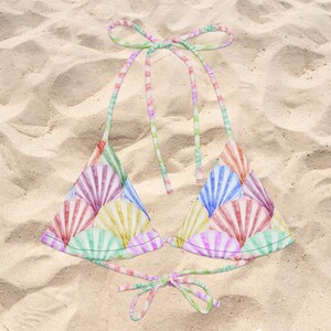 May include: A triangle bikini top featuring a colorful seashell pattern in shades of pink, yellow, blue, and green. The garment includes thin, adjustable halter neck ties and a matching tie closure at the back, all in a coordinating pastel print.