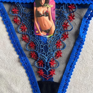 May include: A white ceramic mug with a colorful floral design. The mug features a handle and a wide rim. The flowers are in shades of pink, purple, and yellow. The mug is likely for hot beverages.