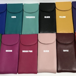May include: Twelve different colored leather eyeglass cases with a flap closure. The colors are cobalt, aqua, turquoise, black, yellow, purple, emerald, orchid, Indian pink, blush, toffee, and coral.