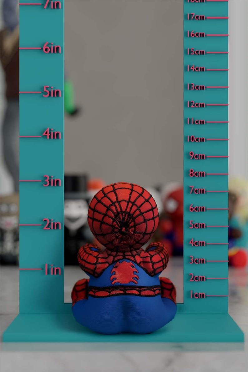K&ouml;nnte beinhalten: Ein Spider-Man-Pl&uuml;schtier, etwa 15 cm gro&szlig;, sitzt vor einer t&uuml;rkisfarbenen Messwand. Das Spielzeug ist rot und blau, mit einem detaillierten Netzmuster auf dem Kopf. Die Tafel hat Zoll- und Zentimetermarkierungen.