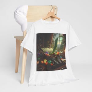 May include: White t-shirt featuring a whimsical illustration of a vintage typewriter with colorful mushrooms and a green, curved plant. The scene is set in a room with a window, creating a fantasy theme.