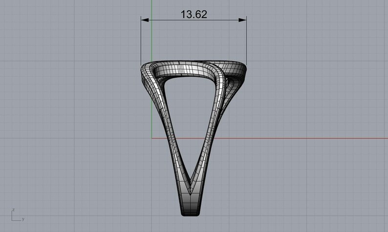 May include: A digital wireframe rendering of a ring featuring a twisted, open-work design. The structure is composed of intersecting lines forming a triangular silhouette. A dimension line at the top indicates a width of 13.62 inches.