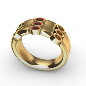 Może przedstawiać: Złoty pierścionek z serią owalnych, czerwonych kamieni szlachetnych. Pierścionek ma unikalny design z prostokątnymi i zakrzywionymi elementami. Kamienie szlachetne są równomiernie rozmieszczone na górze pierścionka.
