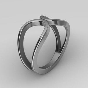 Peut inclure: Une bague argentée au design unique et fluide. La bague présente deux bandes incurvées et entrelacées qui créent une forme ouverte et abstraite. Le métal poli reflète la lumière, soulignant la surface lisse et l'esthétique moderne de la bague.