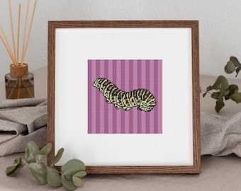 May include: A framed cross-stitch art piece featuring a caterpillar design. The caterpillar is in shades of black, brown, and yellow, set against a purple striped background. The frame is a dark brown color.