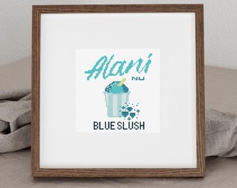 May include: A framed cross-stitch design featuring the words "Alani" in turquoise script above a blue slushie illustration. The words "BLUE SLUSH" are below the image. The frame is a dark brown color.