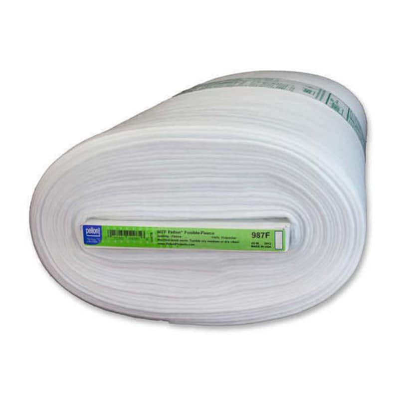 May include: A large roll of white fabric, possibly fleece, is displayed. The fabric is tightly wound, with visible layers. A label with text and a barcode is visible on the roll's core. The fabric appears soft and is likely used for sewing or crafting.