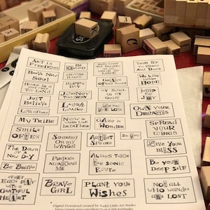 May include: A sheet of paper with 30 different rubber stamp designs. The designs are black and white and feature inspirational quotes and phrases. The paper is white and has a light gray background.