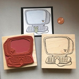 May include: Two wooden stamps, one with a red rubber image of a computer and the other with a black ink image of a computer. Both stamps have a mouse and the word "Trash" on the computer screen.