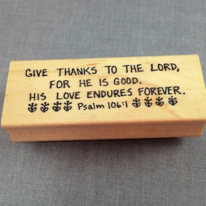 May include: Wooden stamp with the text "GIVE THANKS TO THE LORD, FOR HE IS GOOD. HIS LOVE ENDURES FOREVER. Psalm 106:1" and a series of small flower symbols.