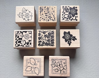 Peut inclure: Ensemble de huit tampons en bois avec des motifs floraux noirs et blancs. Les tampons sont carrés et ont un motif en relief.