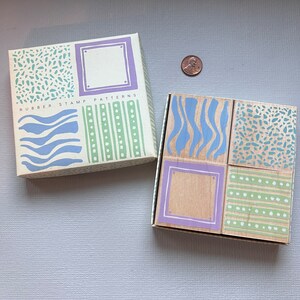 May include: A set of four wooden rubber stamps with different patterns. The stamps are arranged in a 2x2 grid. The patterns include waves, stripes, dots, and a blank space. The stamps are labeled "Rubber Stamp Patterns".