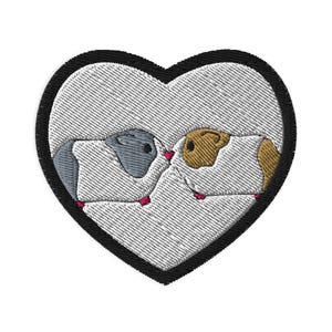 Puede incluir: Parche bordado con dos cobayas dentro de un corazón blanco con borde negro. Una cobaya es gris, la otra marrón y blanca. Ambas tienen patas rosas y se miran. El parche está sobre un fondo blanco.