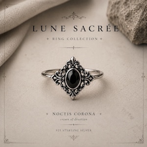 May include: A sterling silver ring with an oval black gemstone set in an ornate, filigree design. The ring is part of the "Ring Collection" and is labeled "Noctis Corona" with "925 Sterling Silver" text.