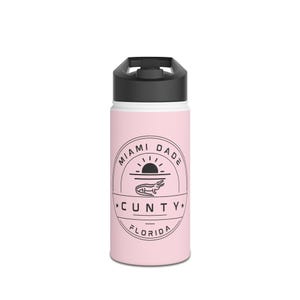 May include: A light pink water bottle with a black lid and a white band. The bottle features a circular graphic with the words "Miami Dade" and "Florida", along with an alligator illustration and the word "CUNTY".