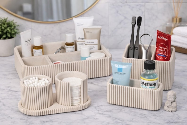 May include: Beige ribbed bathroom organizers holding toiletries, toothbrushes, toothpaste, and mouthwash. The set includes a tray with containers for cotton swabs and pads, and a larger tray with skincare products.