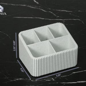 May include: A light gray, rectangular organizer with six compartments. The organizer is 5.25 inches long, 4.25 inches wide, and 2.25 to 3.00 inches high. The sides have a vertical ribbed design. The logo "VALAYA" is in the upper left corner.