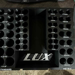 May include: Black plastic socket organizer with labeled holes for standard and metric sizes. The standard side includes sizes from 7/16" to 1-1/4", and the metric side includes sizes from 10mm to 24mm. The LUX logo is visible.