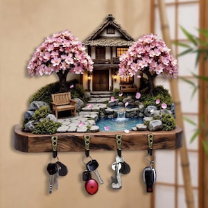 May include: A decorative key holder featuring a miniature Japanese garden scene. The scene includes a house, cherry blossom trees, a pond, and a waterfall. The key holder has four hooks and is made of wood.