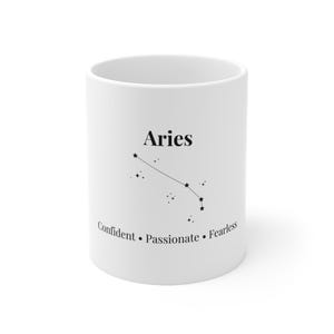 Könnte beinhalten: Weißer Keramikbecher mit dem Sternbild Widder in Schwarz. Das Wort "Aries" steht über dem Sternbild, darunter die Worte "Confident, Passionate, Fearless".