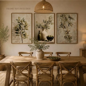 May include: A set of three wall art prints featuring olive branch illustrations and a still life with a vase and bowl. The prints are displayed in a dining room setting. The text "FRAME NOT INCLUDED" is visible in the upper left corner.