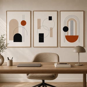 Puede incluir: Tres impresiones artísticas abstractas enmarcadas con formas geométricas en tonos neutros de beige, negro y óxido. La obra de arte se exhibe sobre un escritorio de madera con un portátil, libros y una lámpara. La habitación tiene una estética moderna y minimalista.