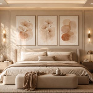 Puede incluir: Un dormitorio con una cama grande con ropa de cama beige, un banco largo tapizado a los pies y tres cuadros de pared enmarcados que muestran formas florales y circulares abstractas en tonos beige, crema y terracota sobre una pared panelada.