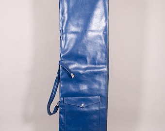 Puede incluir: Una funda larga y rectangular de vinilo azul con un bolsillo y un asa. La funda tiene una franja roja en la parte inferior y un cierre plateado. La funda está diseñada para guardar un objeto largo y delgado.