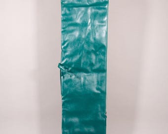 Puede incluir: Un estuche largo de color verde azulado, similar al cuero, con forma rectangular. El estuche tiene un cierre de cordón y un pequeño bolsillo en la parte inferior. El material tiene un aspecto texturizado. El estuche está diseñado para guardar un objeto largo y estrecho.