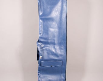 Puede incluir: Una funda de guitarra azul de vinilo con cierre de cremallera y un bolsillo frontal. La funda tiene una correa para el hombro y un ribete rojo en la parte inferior. La funda está diseñada para proteger una guitarra durante el transporte.