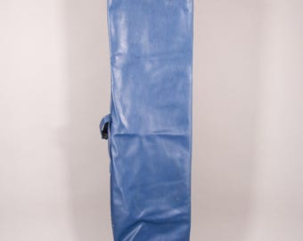 Puede incluir: Una bolsa larga y rectangular de vinilo azul con cierre de cremallera y asa lateral. La bolsa es de color azul medio liso y parece estar vacía. La bolsa está diseñada para guardar un objeto largo y estrecho.