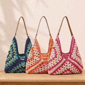 Peut inclure: Trois sacs de style hobo fabriqués en fil crocheté avec un motif de carrés de grand-mère. Chaque sac présente une forme triangulaire, une bandoulière unique en similicuir marron et des palettes de couleurs distinctes : bleu marine et vert, orange et rose, et rose et beige.
