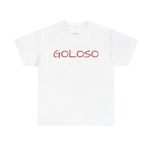 Può includere: T-shirt bianca con la scritta "GOLOSO" in rosso, centrata sul petto. Il testo è in stile scritto a mano. La maglietta è realizzata in un materiale morbido.