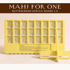 May include: A yellow acrylic board for Mahjong, with the text "MAHJ FOR ONE" and "ROLL OR 1 ROLL OR 2 ROLL OR 3" in yellow. The board has a scalloped edge and a stand. Instructions are printed at the bottom.