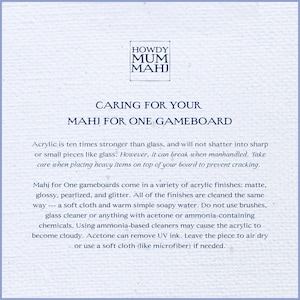 May include: A light blue paper with text about caring for a Mahj for One gameboard. The text includes cleaning instructions and material information. The Howdy Mum Mahj logo is at the top.