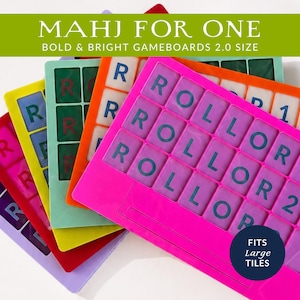 Peut inclure: Plusieurs plateaux de jeu color&eacute;s, dont rose, orange, vert, jaune, rouge et violet. Les plateaux comportent des tuiles lettr&eacute;es et le texte "ROLLOR", "1" et "2". Le texte "MAHJ FOR ONE" et "FITS Large TILES" est &eacute;galement visible.