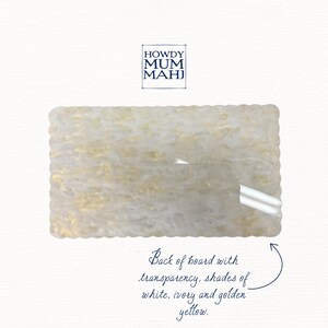 May include: Rectangular board with a scalloped edge, featuring a translucent design with white, ivory, and golden yellow hues. The text "HOWDY MUM MAHJ" is in the upper left corner, with additional text describing the board's features.